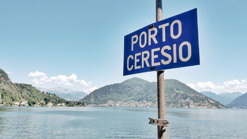 Information sign by sea against sky