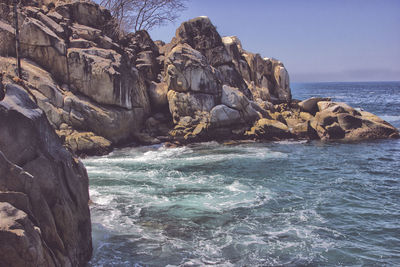 Rock formation in sea against clear sky