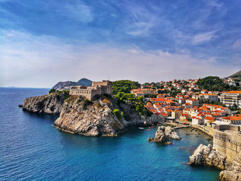 View of houses on coast against cloudy sky