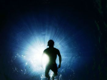 Low angle view of silhouette man swimming in sea 