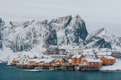 Buildings by snowcapped mountains against sky