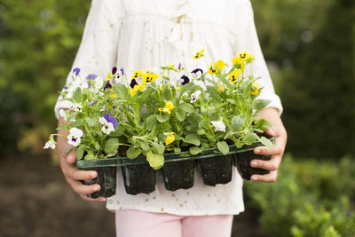 Midsection of woman holding bouquet of flowering plant