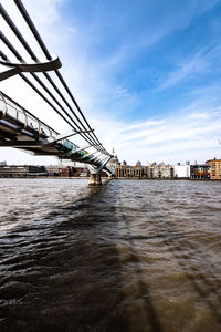 Bridge over river against sky in city