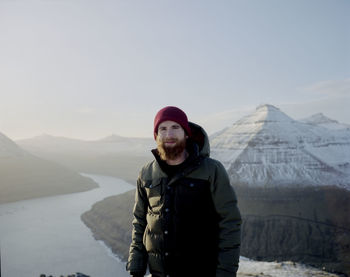 Man standing on snow covered mountain against sky