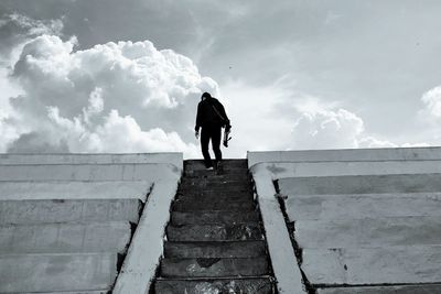 Rear view of man standing on staircase against sky