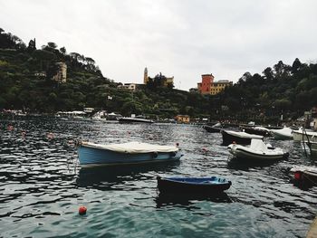 Boats moored on sea against buildings in city