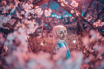 Portrait of woman standing by cherry blossom tree