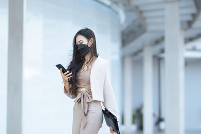 Young woman standing against building