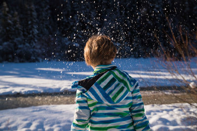 Rear view of boy standing in snow