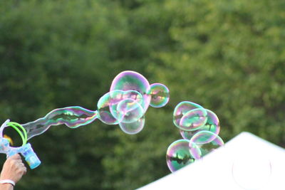 Cropped hand of person holding wand with bubbles