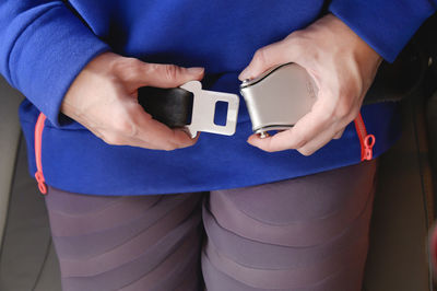 Midsection of woman holding camera while standing against blue wall