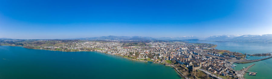 High angle view of city by sea against blue sky