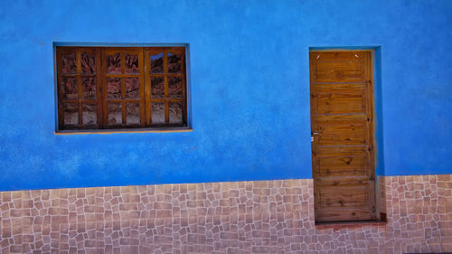 Low angle view of blue window on wall of building