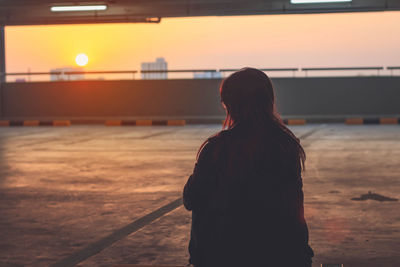 Rear view of woman standing at parking lot