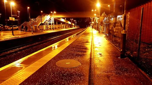 Illuminated railroad tracks against sky at night