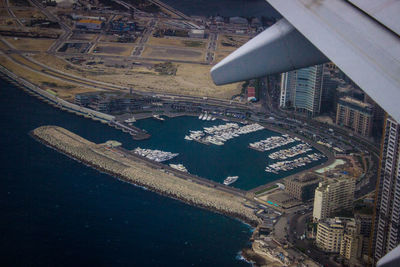 High angle view of airplane flying over buildings in city