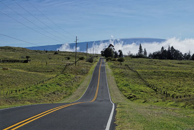 Road amidst field against sky