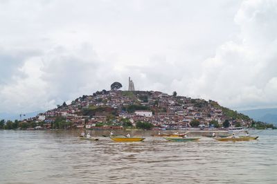 Buildings by sea against sky