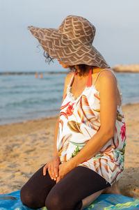 Woman wearing hat while sitting on beach