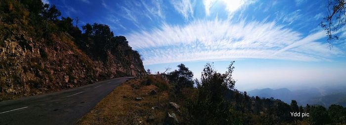 Road by trees against sky