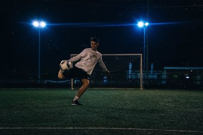 Man playing soccer on field at night