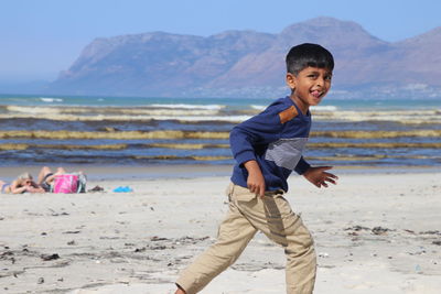 Side view portrait of boy running at beach