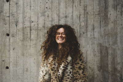 Portrait of smiling young woman against wall