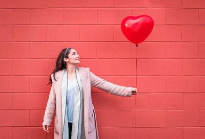 Rear view of woman with heart shape on red wall