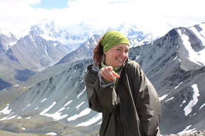 Portrait of young woman standing on snowcapped mountain