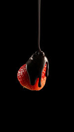 Close-up of strawberry hanging over black background