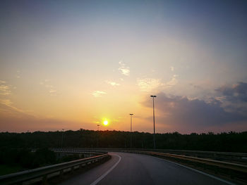 Cars on street against sky during sunset