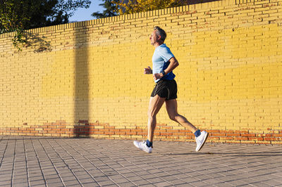 Full length of woman running on footpath in city