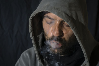 Close-up portrait of man wearing mask against black background