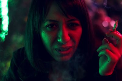 Close-up portrait of woman holding cigarette