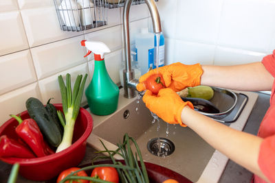 Washing fresh vegetables in the kitchen under cold running tap water