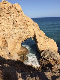 Rock formation in sea against clear sky