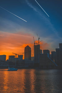 Modern cityscape against sky during sunset