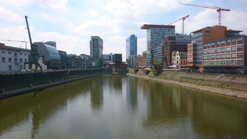 Reflection of buildings in river against sky in city