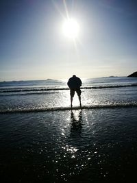 Silhouette man walking on beach against clear sky