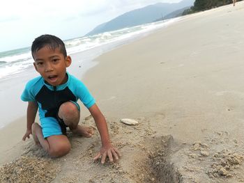 Portrait of happy boy playing on beach against sky