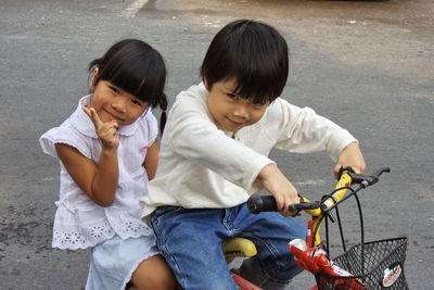 Rear view of siblings sitting on road