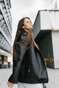 Portrait of young woman standing against building