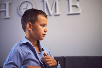 Portrait of boy looking away while standing against wall