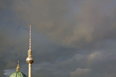 Communications tower and church against cloudy sky