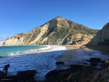 Scenic view of sea and mountains against clear blue sky