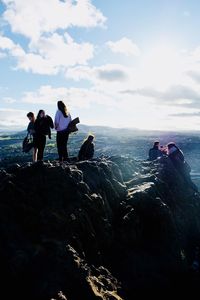 People on rock by sea against sky