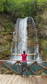 Rear view of man sitting against waterfall