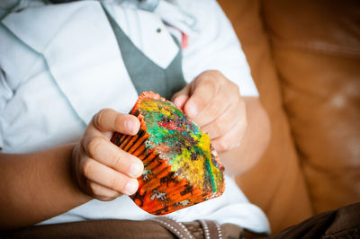 Midsection of boy holding cupcake at home