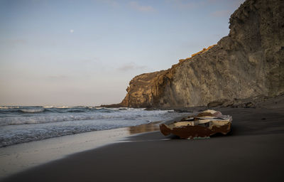 Rock formation on beach with an abandoned boat in cabo de gata, almeria, spain, against sky