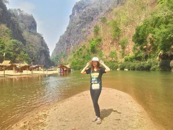 Woman standing on rock by river against mountains